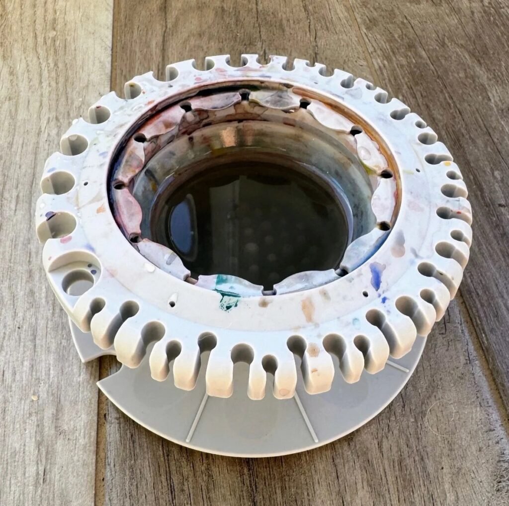 Photograph of a grey paint puck collapsible water bowl from the side, containing water